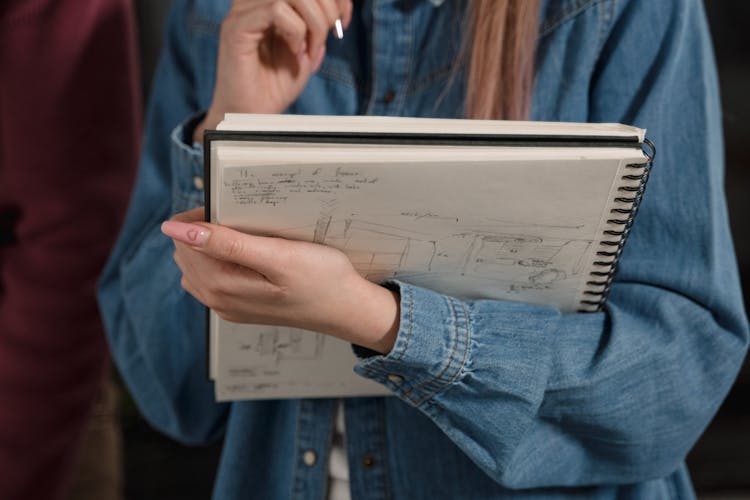 Person In Denim Jacket Holding A Sketch Pad