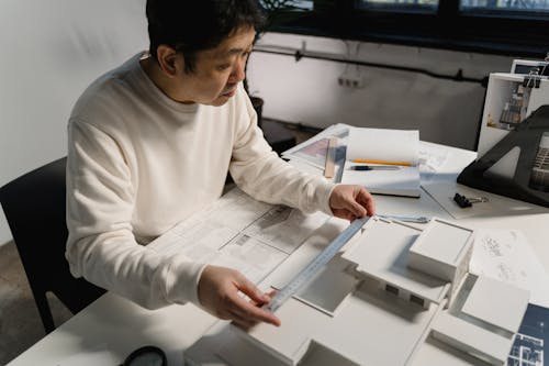 Man in White Long Sleeve Shirt Getting Measurement of a Scale Model with Ruler