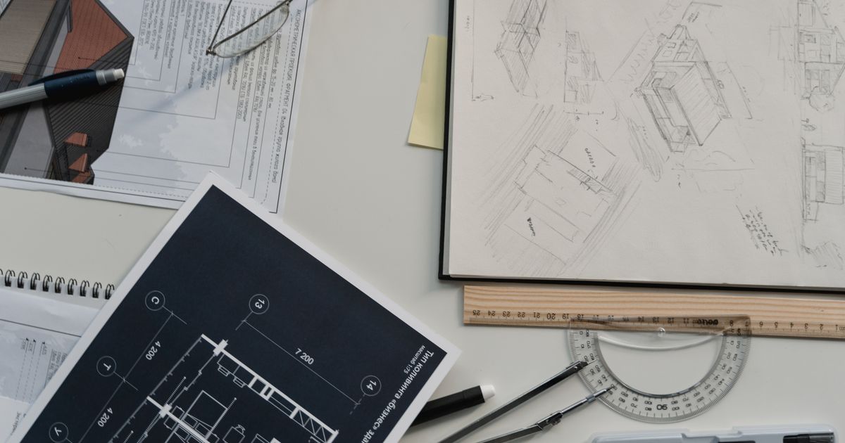 A designer's desk with compass, blueprints, and drawing tools, representing reading your Destiny Matrix career and profession direction