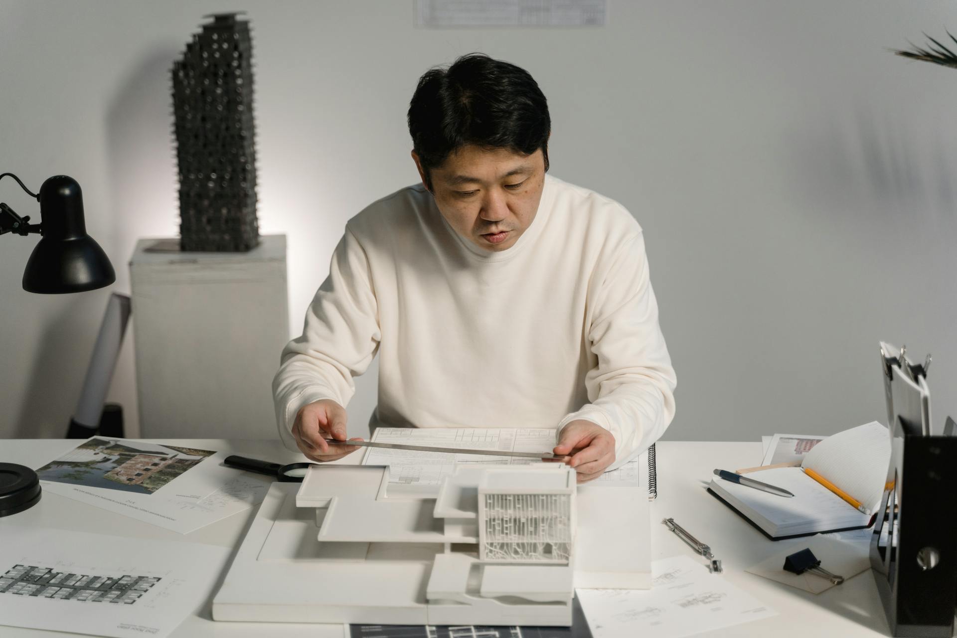 Man in White Long Sleeve Shirt Measuring an Architectural Scale Model