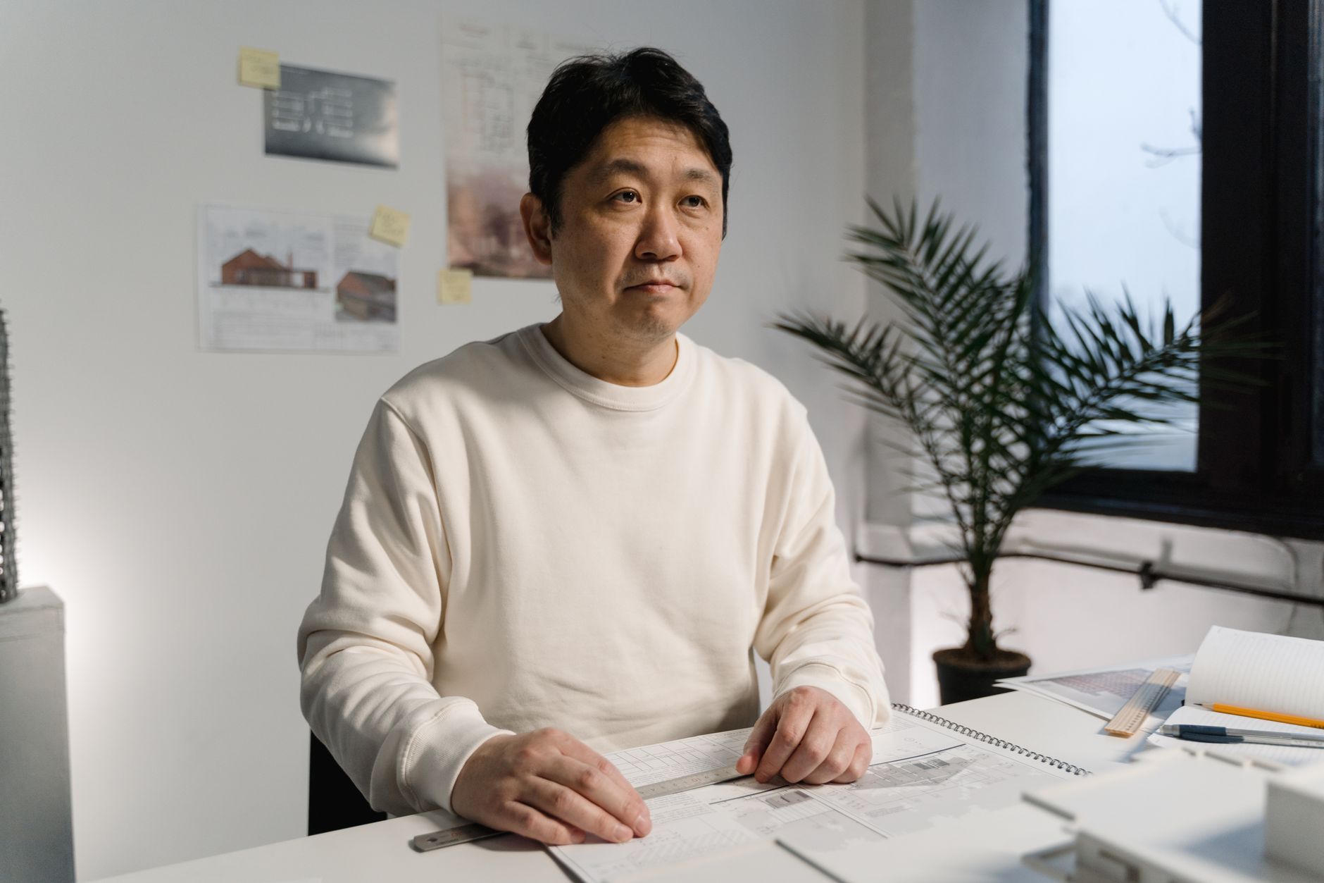 Architect focused on plans in a modern office setting, surrounded by design materials.