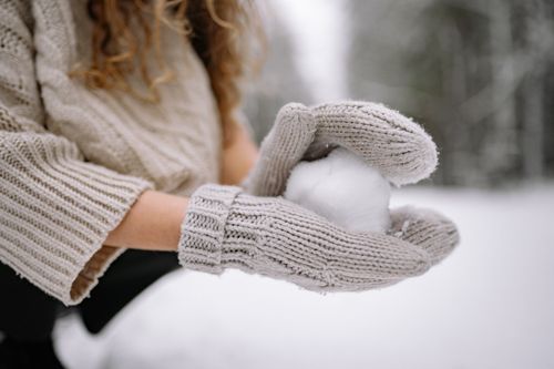 Free Close-up of knitted gloves holding a snowball, capturing the essence of winter fun. Stock Photo