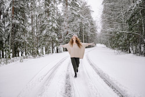 Free Happy Woman Walking on a Snow Covered Road in Winter  Stock Photo