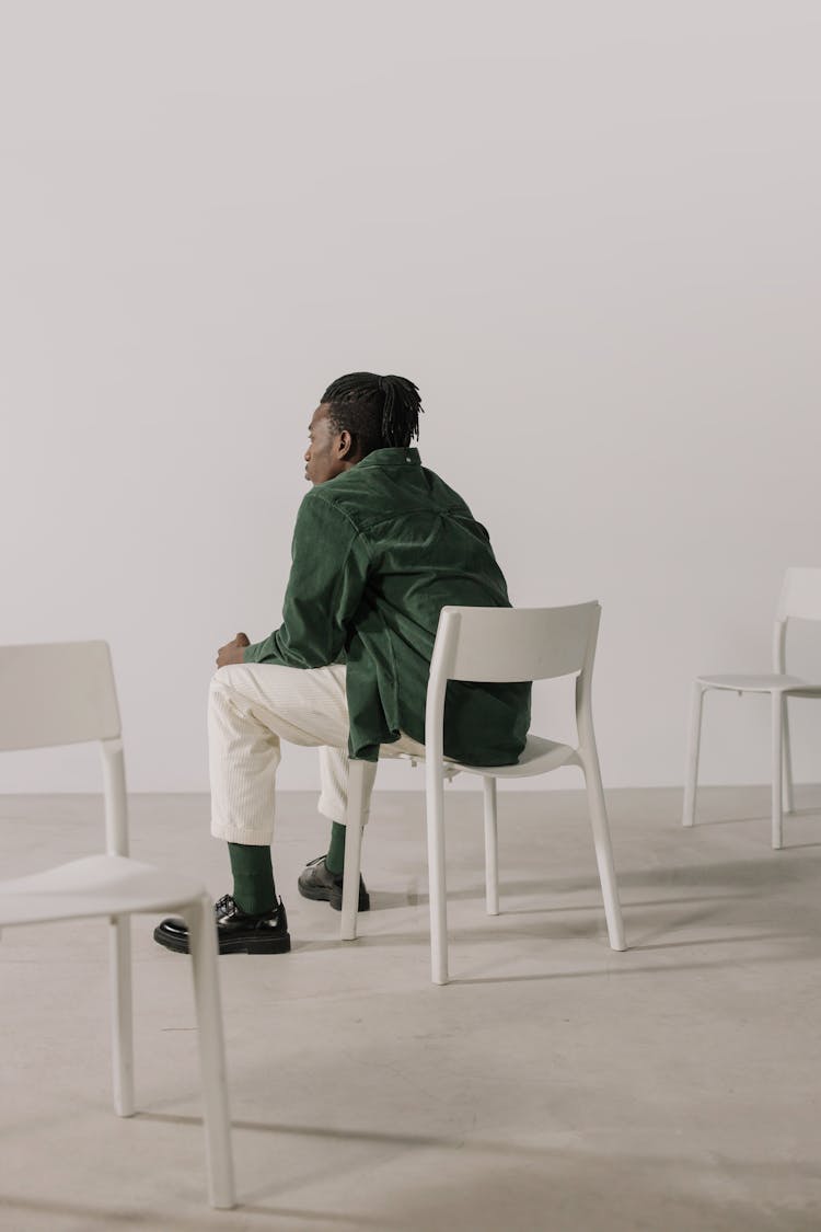 A Person In Green Dress Shirt Sitting On White Chair