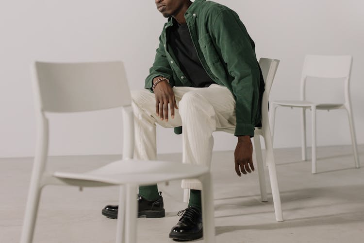 A Man In Green Jacket Sitting On White Plastic Chair