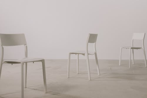 Three White Chairs Standing in a Studio with White Walls