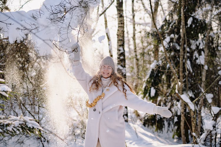 Woman Tugging On Branch Covered In Snow