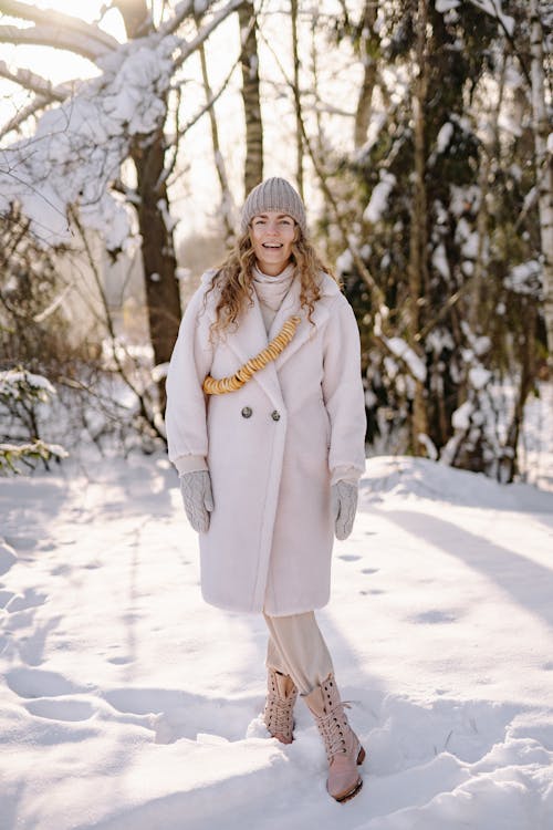 Photo of a Woman in a Coat Standing on White Snow