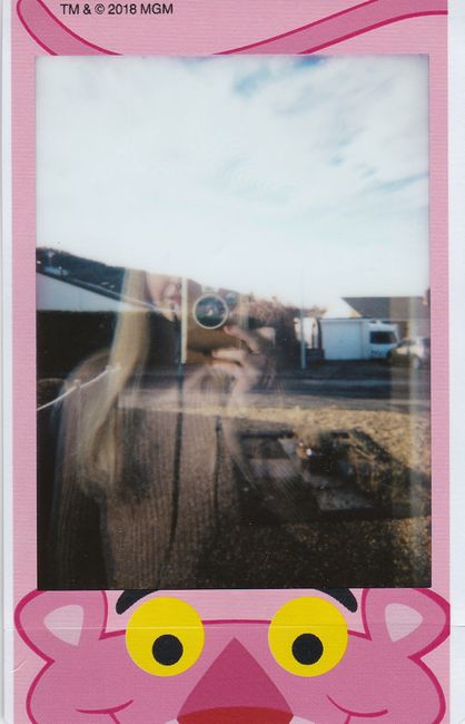 Artistic self-portrait using reflection captured in a stylish Polaroid frame outdoors.