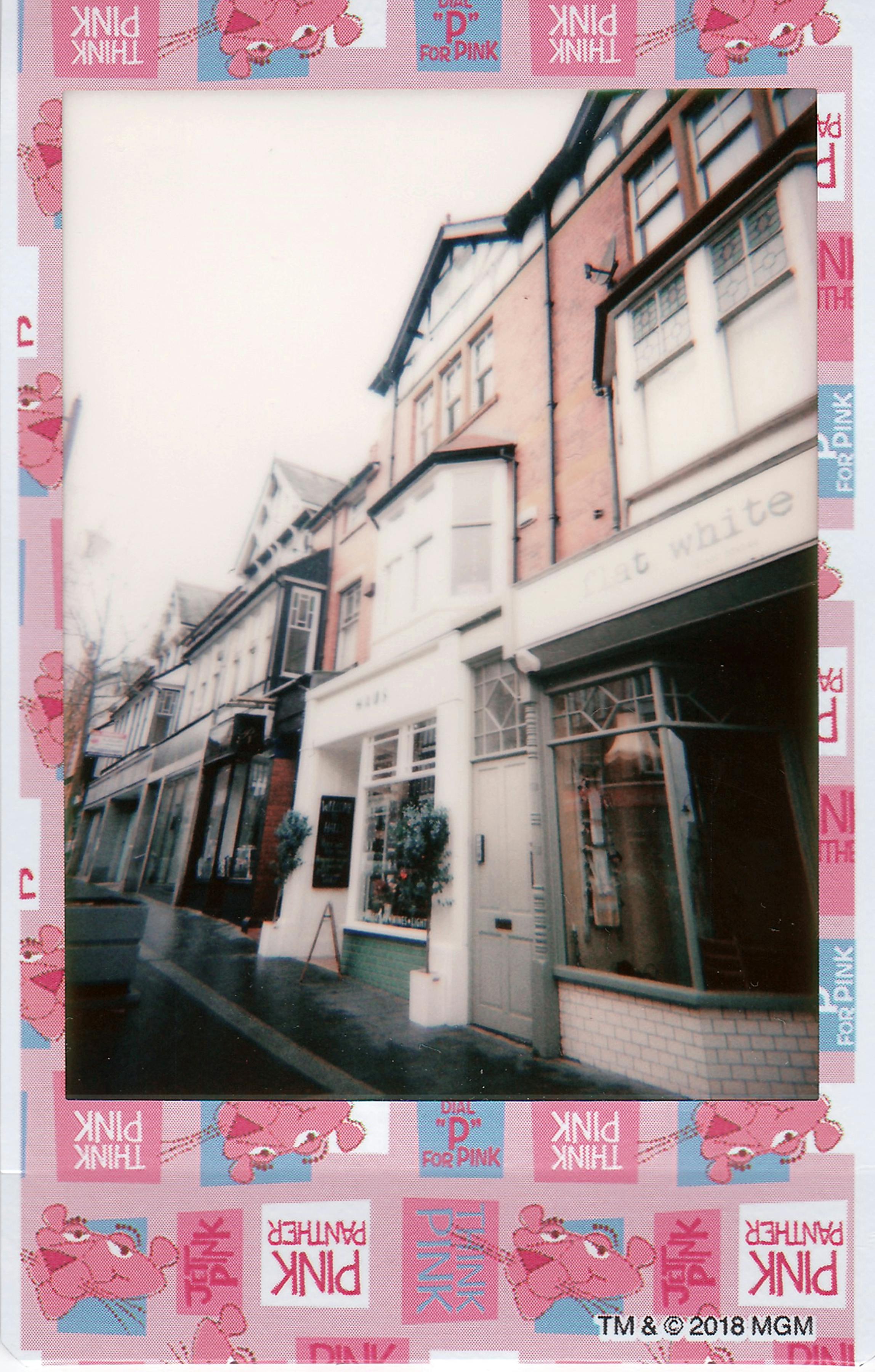 Polaroid image of an old European street with charming storefronts.