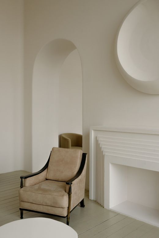 Pale armchair beside a plaster fireplace — photo by Ksenia Chernaya on Pexels