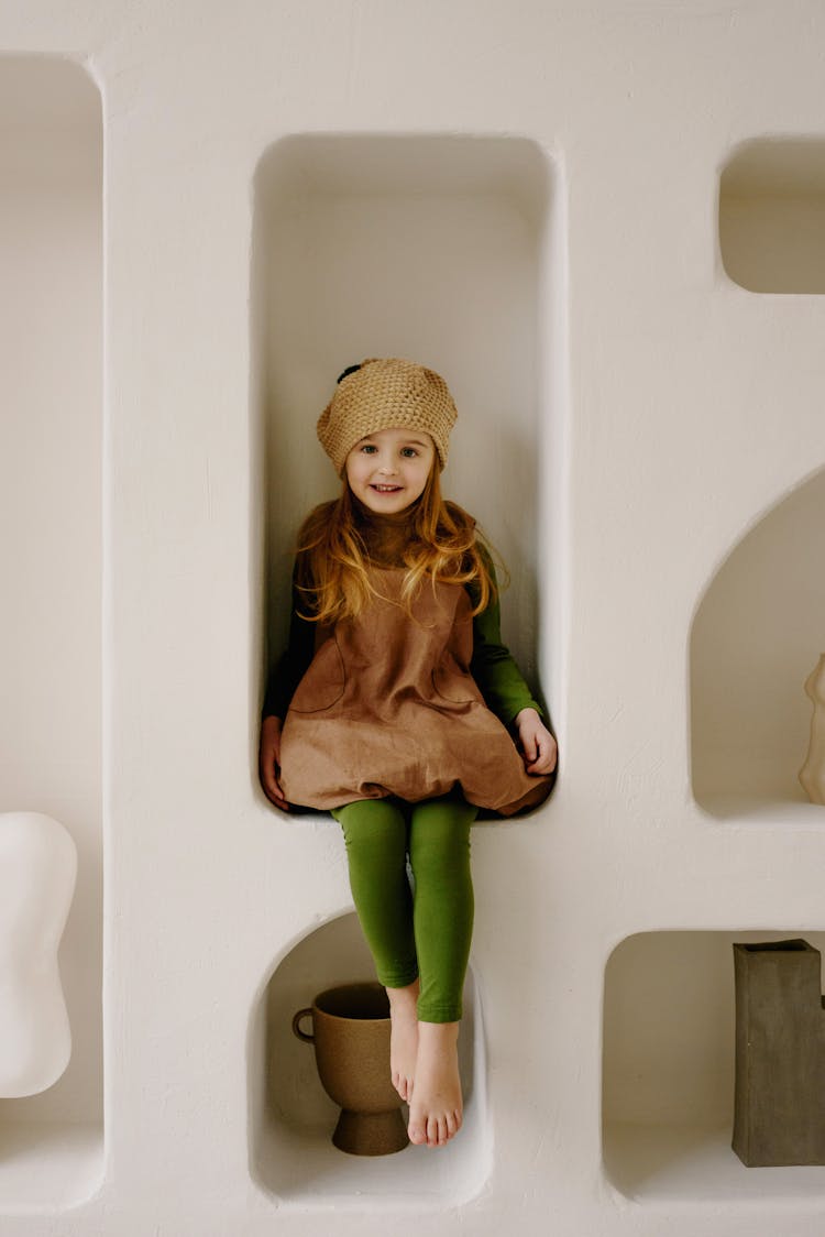 A Girl Sitting On A Wall Shelf