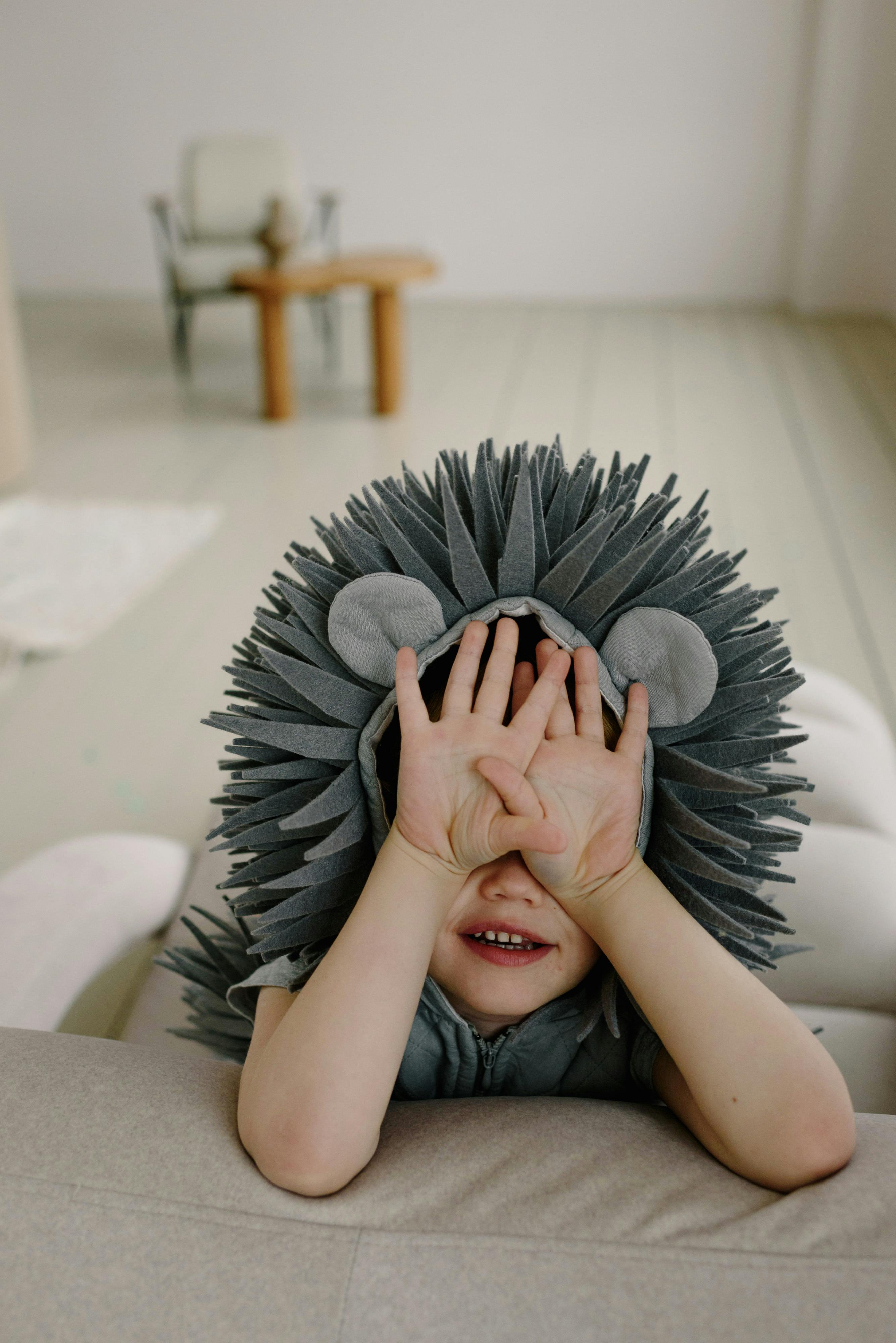 a child in costume covering eyes with hands