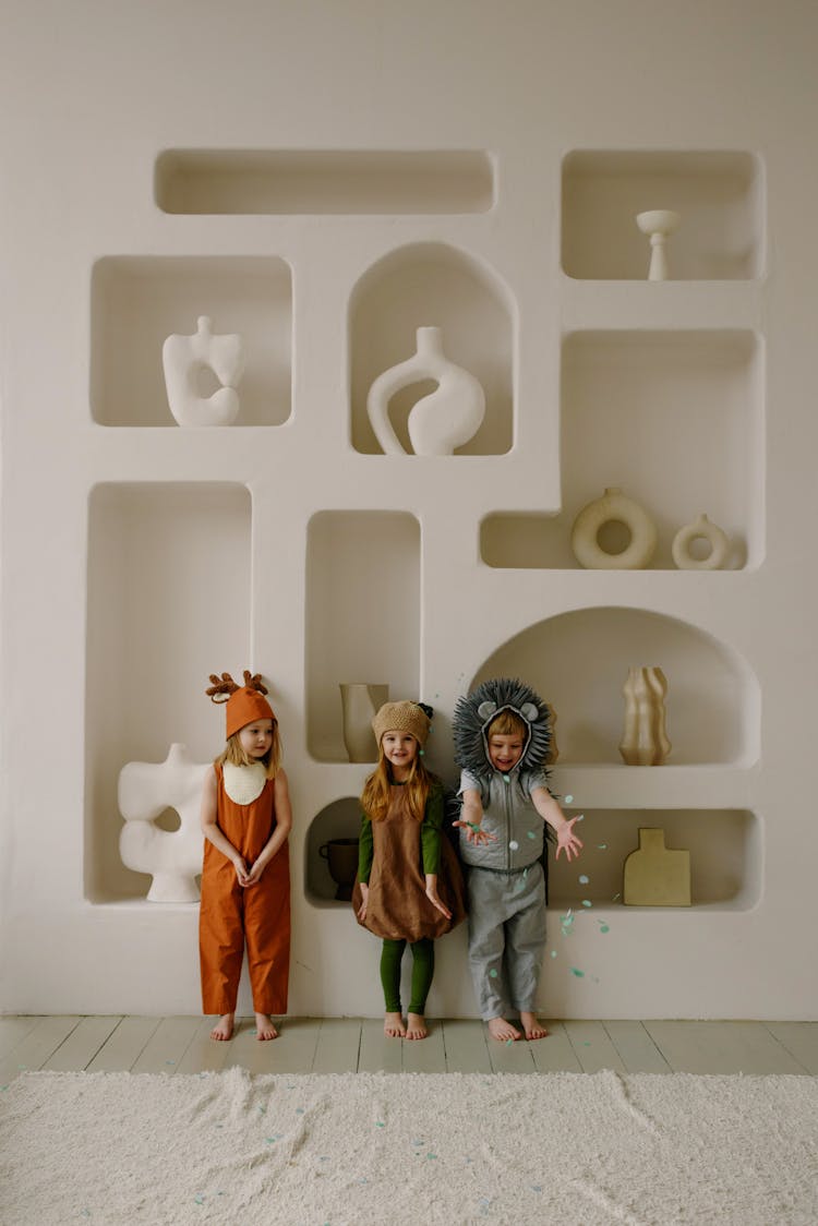 Kids Wearing Costumes Standing In Front Of Customized Shelf