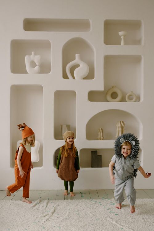 Free Three children in animal costumes play indoors against a modern white background. Stock Photo