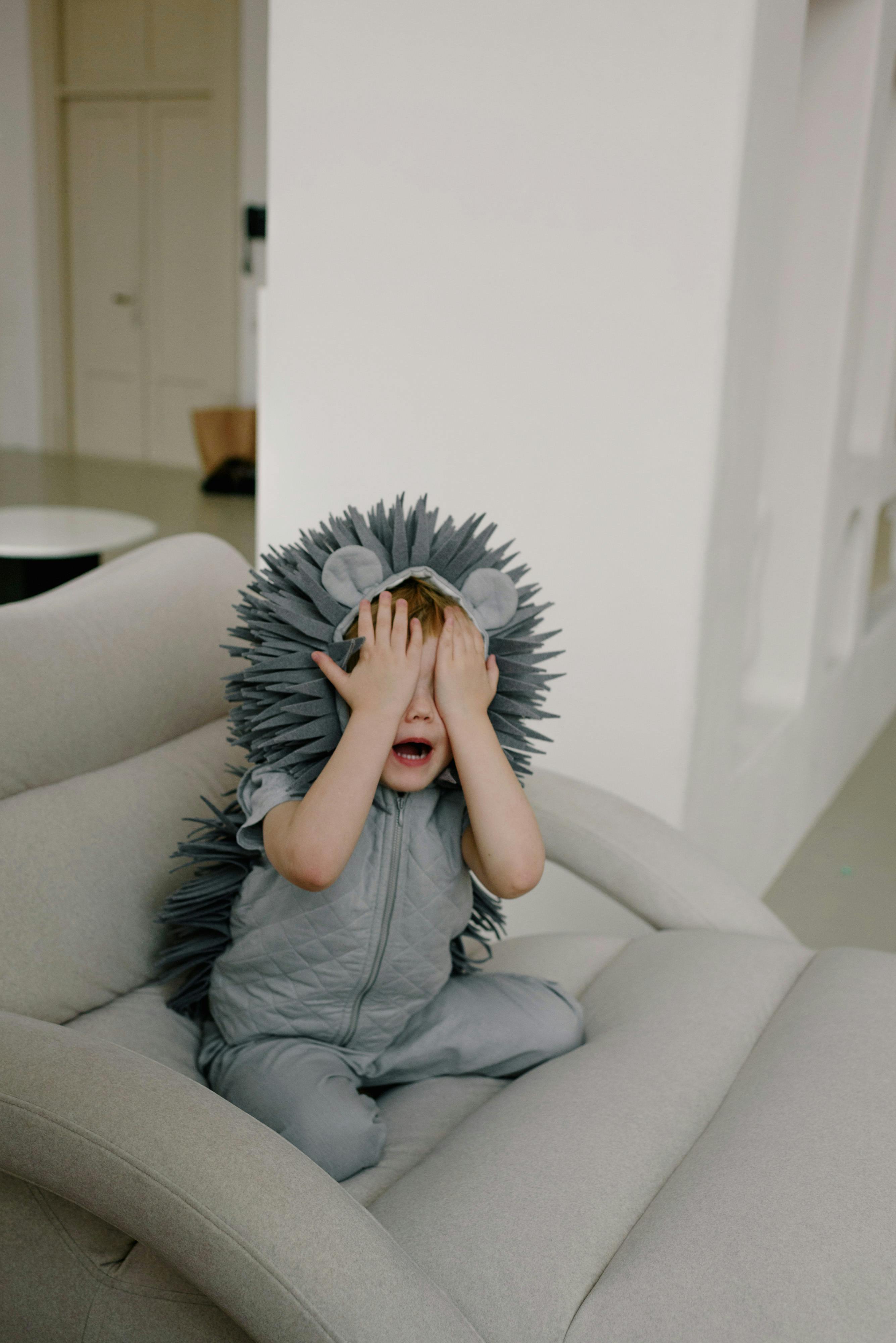 a boy wearing costume covering his eyes