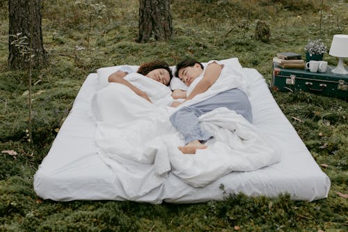 Free A Couple Lying Down on a Mattress Outdoors Stock Photo