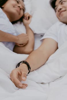 A couple happily relaxing in bed during a bright morning, exchanging smiles and warmth.