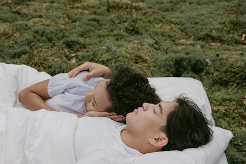 Man and Woman Lying in Bed Linen on Grass