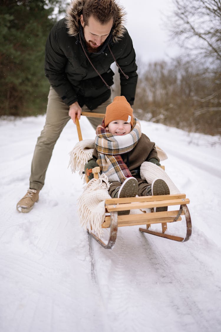 Man Pushing Son On A Sledge 