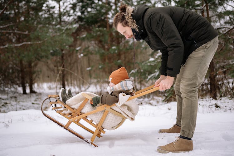 Father Sledding With Child In Winter Forest