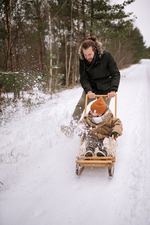 Smiling Father and Child Sledding in Park