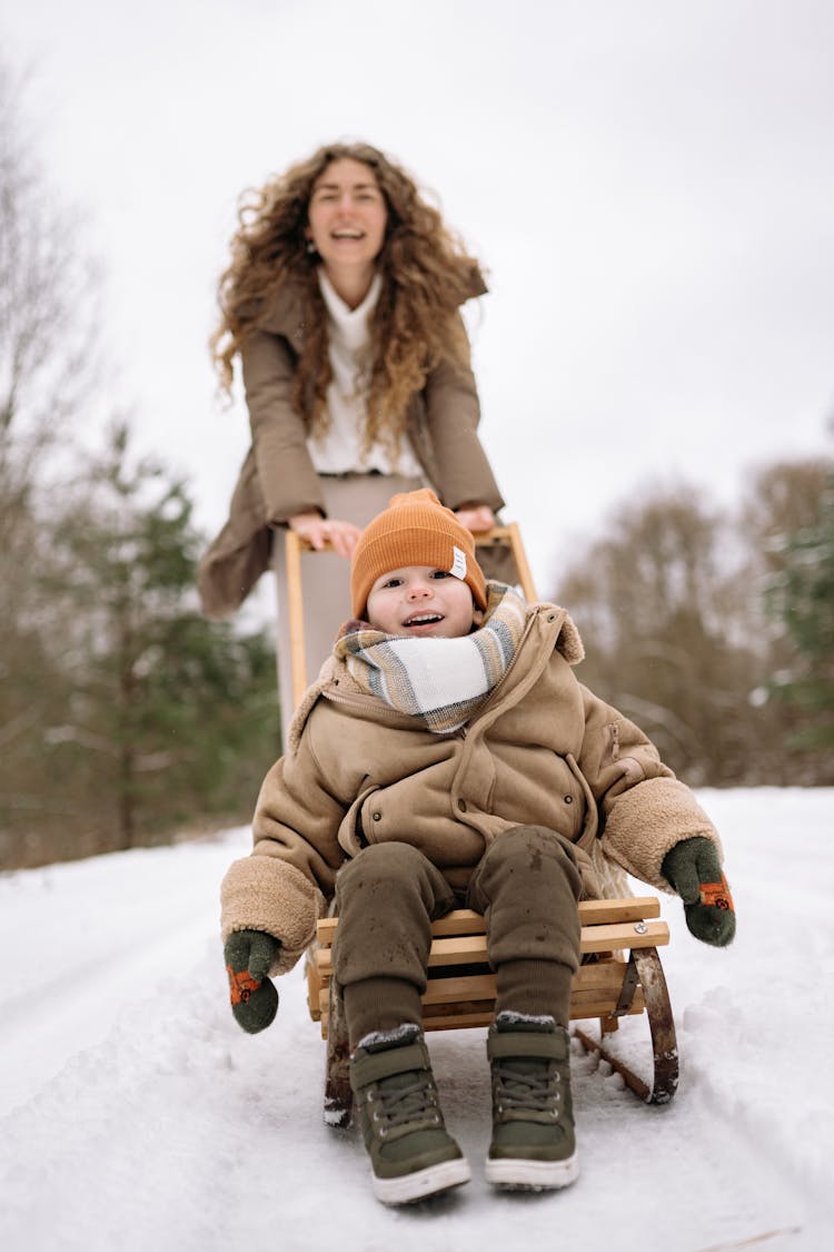 Mother Pushing Her Son On The Sledge 