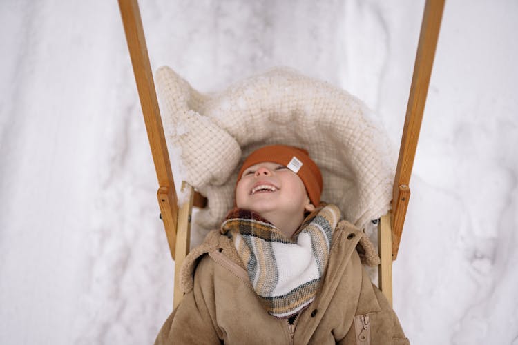 Smiling Small Child On Sleds In Winter