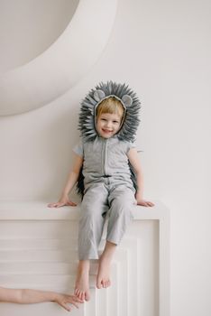 Adorable child in a hedgehog costume sitting indoors, smiling cheerfully.