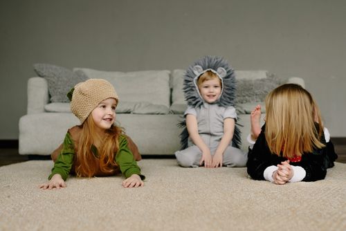 Free Three children having fun in animal costumes on a living room floor, showcasing playful joy. Stock Photo