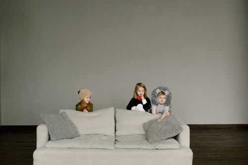 Free Three children in cute animal costumes sit on a couch in a minimalist indoor setting. Stock Photo