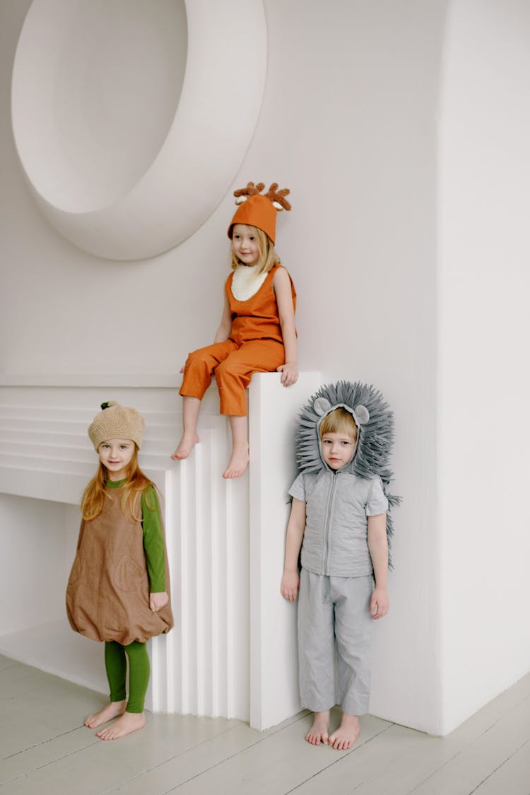 Kids Wearing Costumes Leaning On White Wall