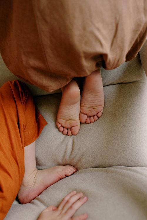 Free Top view of children's bare feet resting on a soft cushioned sofa, creating a cozy home atmosphere. Stock Photo