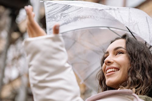 A Low Angle Shot of a Smiling Woman Holding an Umbrella