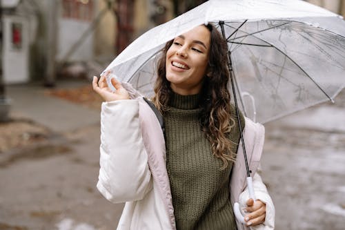 A Smiling Woman in White Jacket Holding an Umbrella