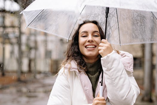 Portrait of a happy woman smiling under a clear umbrella on a rainy day outdoors.