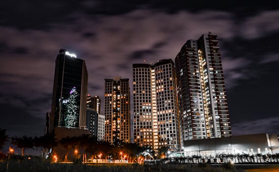 Majestic city skyline with illuminated skyscrapers under a cloudy night sky.