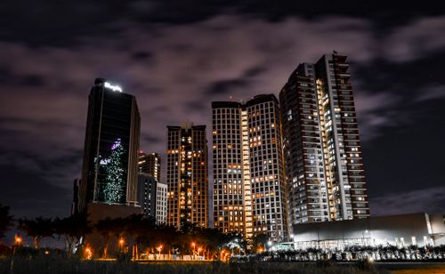 Free Majestic city skyline with illuminated skyscrapers under a cloudy night sky. Stock Photo