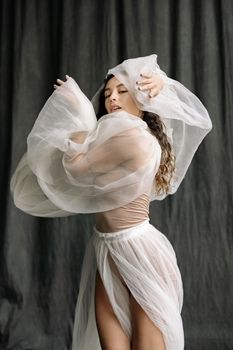 Graceful woman wrapped in translucent fabric exudes elegance and poise, creating a mesmerizing artistic portrait.