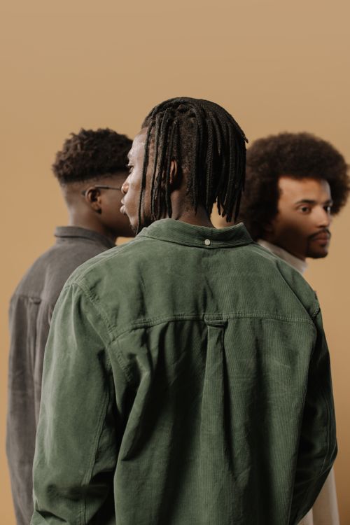 Free Three men with diverse hairstyles, including dreadlocks and afro, standing against a neutral background. Stock Photo