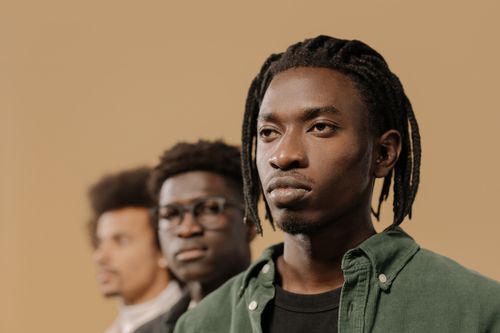 Free Stylish portrait of three men with unique hairstyles in a studio setting. Stock Photo
