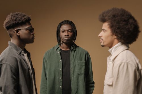 Free Stylish studio portrait of three fashionable young men with various hairstyles and green attire. Stock Photo