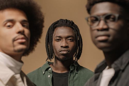 Free Close-up portrait of three black men with varied hairstyles in a neutral setting. Stock Photo