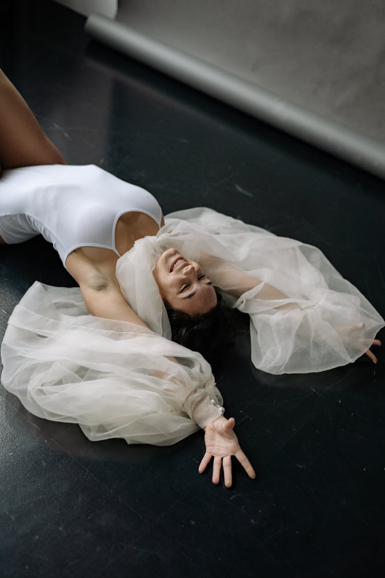 A Woman Smiling And Stretching While Lying On The Floor