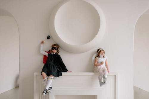 Free Two Children in Costumes Leaning on a White Wall Stock Photo