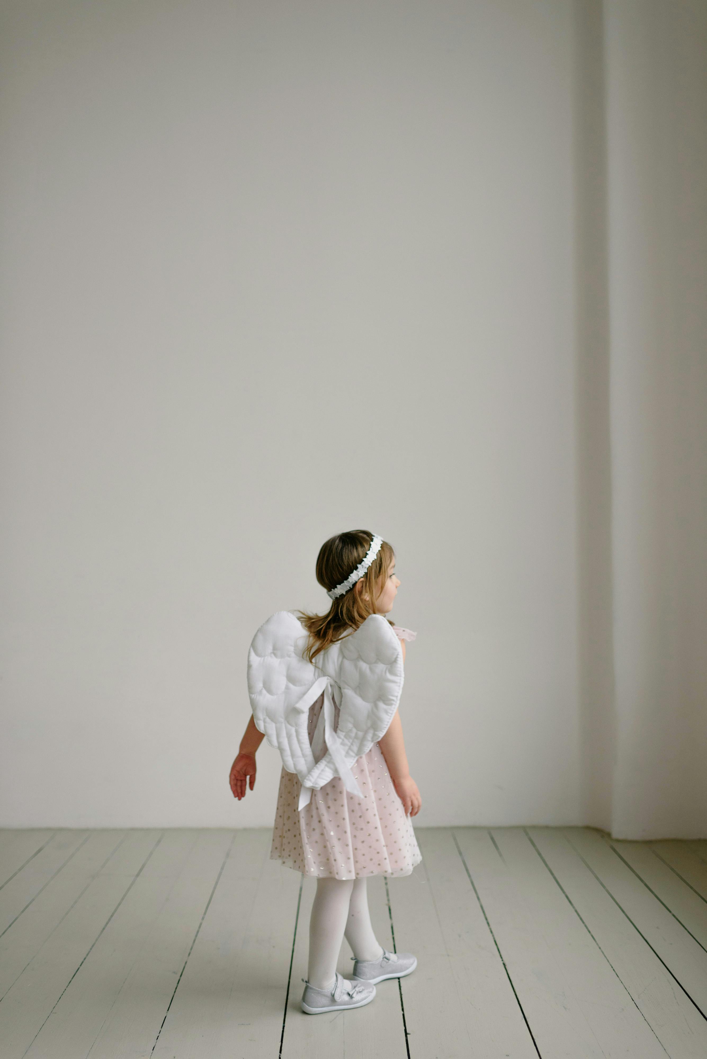 girl in angel costume in white room
