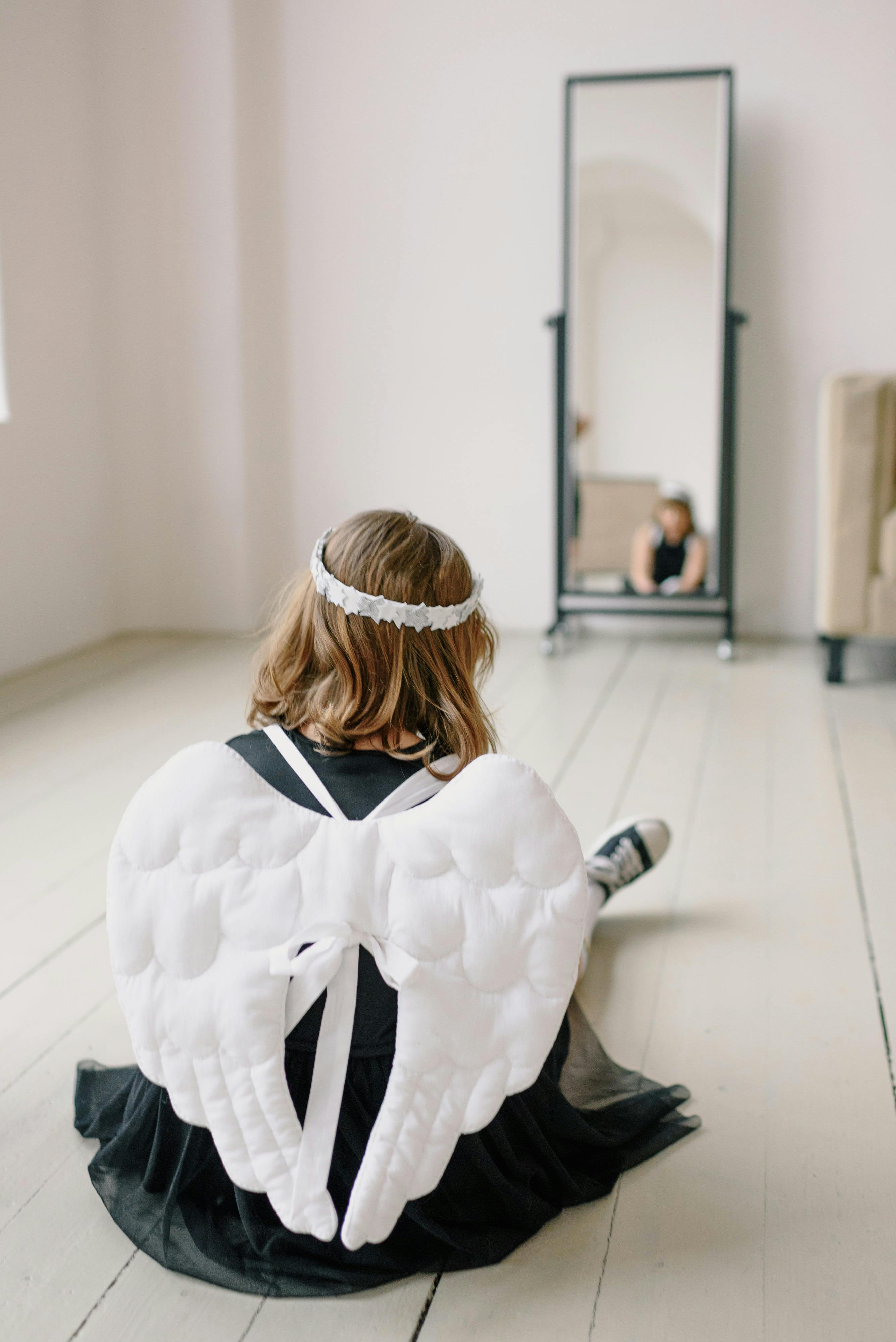 a girl in black angel costume sitting on the floor