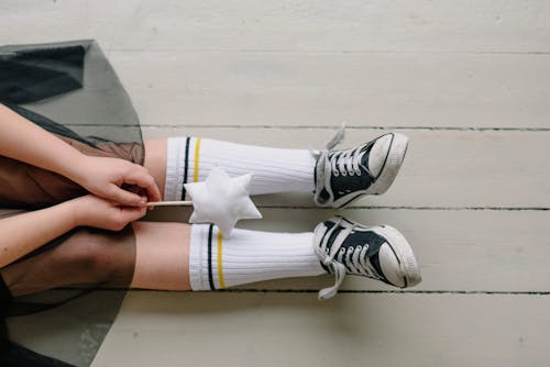 A Child Wearing White High Socks Holding White Stick with Star