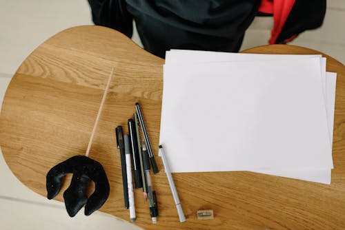 White Paper and Pens on Wooden Table