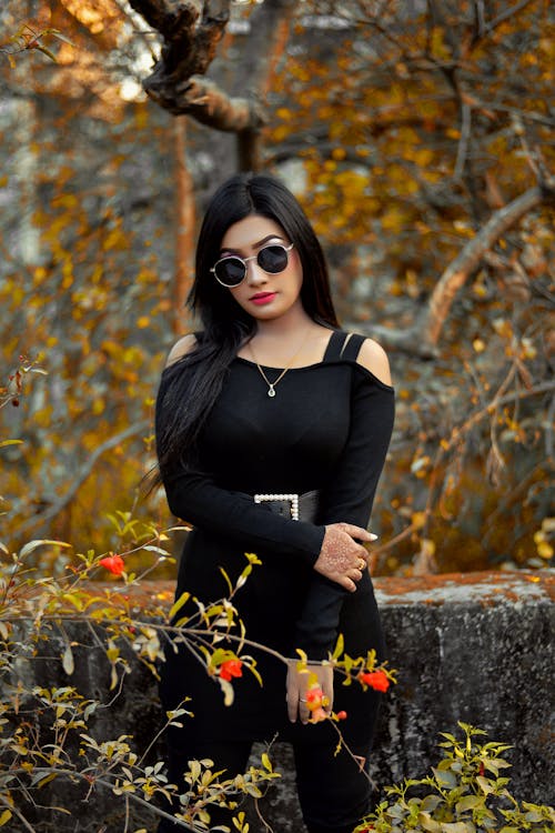 Woman in Black Dress Wearing Black Sunglasses Standing Near  Concrete Wall 